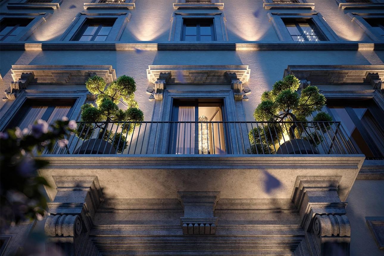 The illuminated façade and planted balcony of a historic city building at dusk.