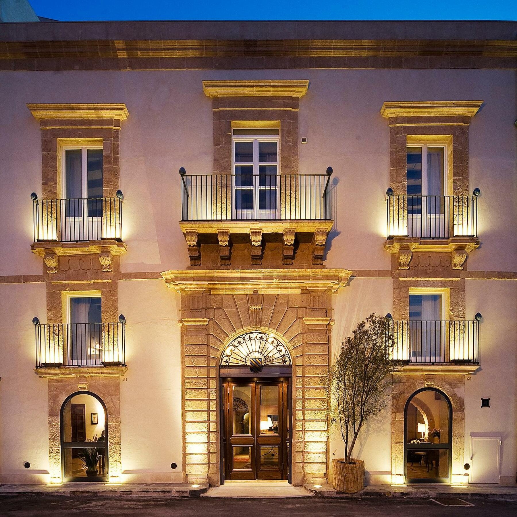 The illuminated façade of a grand classical building at dusk.
