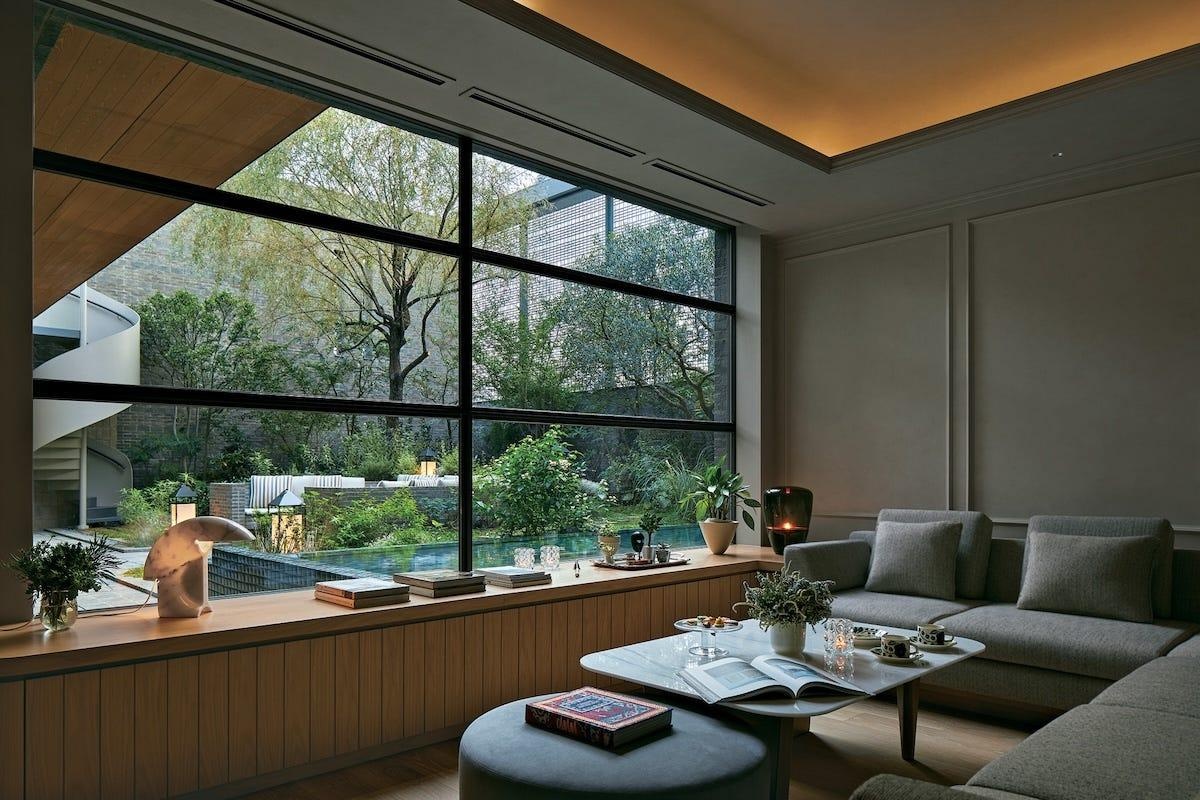 A garden-facing lounge with a large picture window and quiet furnishings.