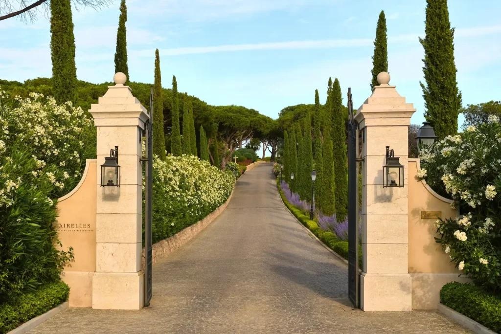 Open gates onto a cypress-lined private drive at dusk.