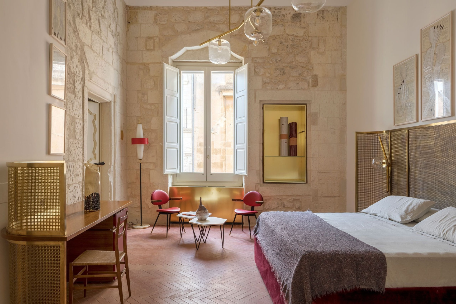 A stone-walled bedroom with contemporary furniture and large windows.