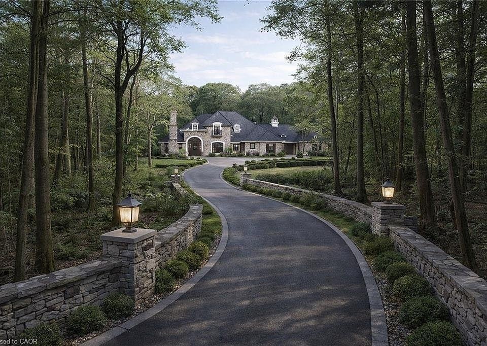 A winding drive leading to a stone estate within dense northern forest.
