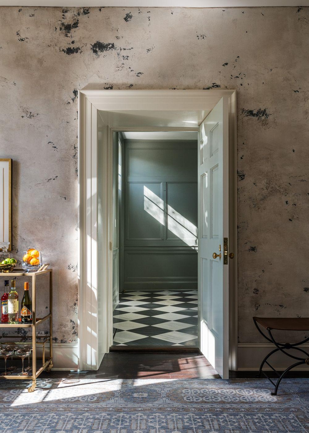 A doorway opening onto a chequered-floor room with a drinks trolley.