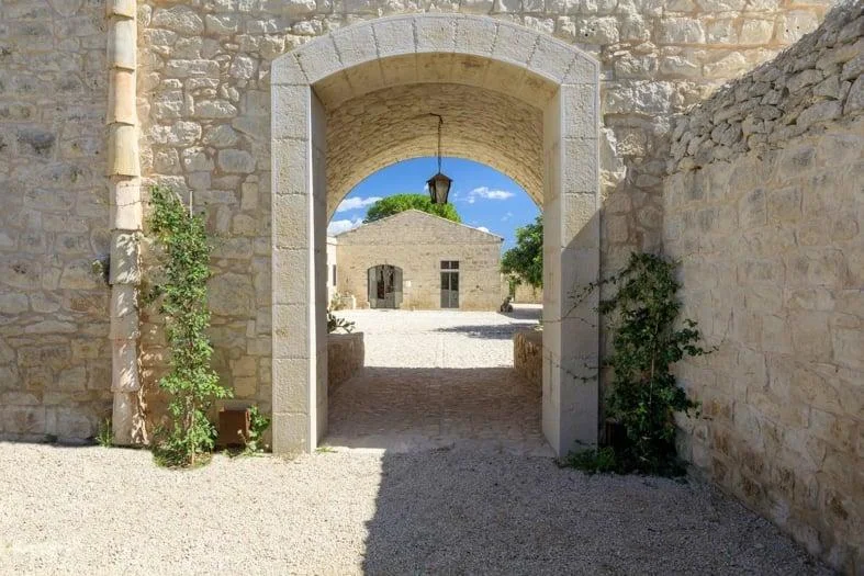 A stone archway opening onto a sunlit courtyard.
