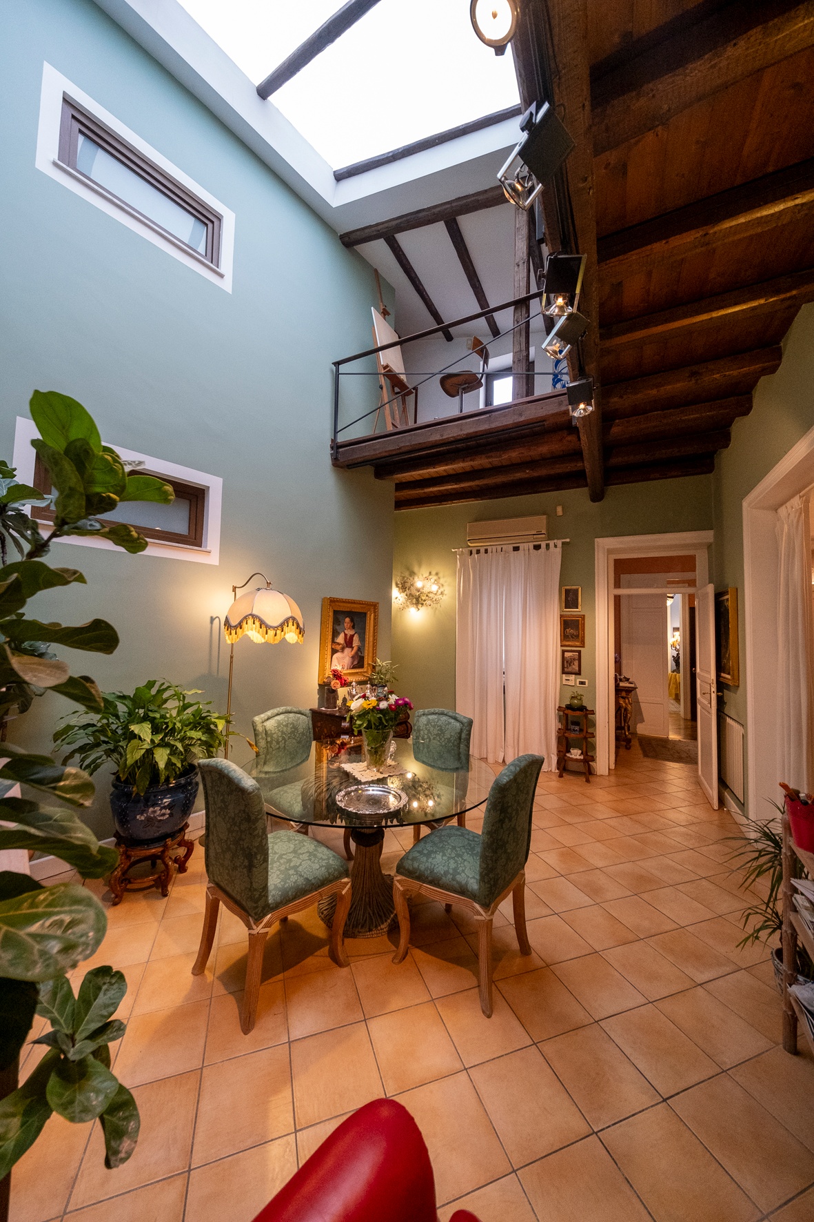 A skylit room with a timber staircase and a long dining table.